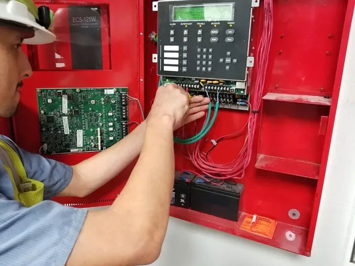 ASAP Fire Protection technician wiring a commercial fire alarm control panel