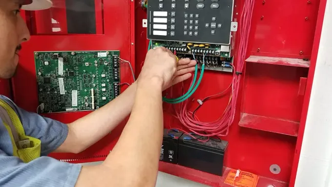 ASAP Fire Protection technician wiring a commercial fire alarm control panel